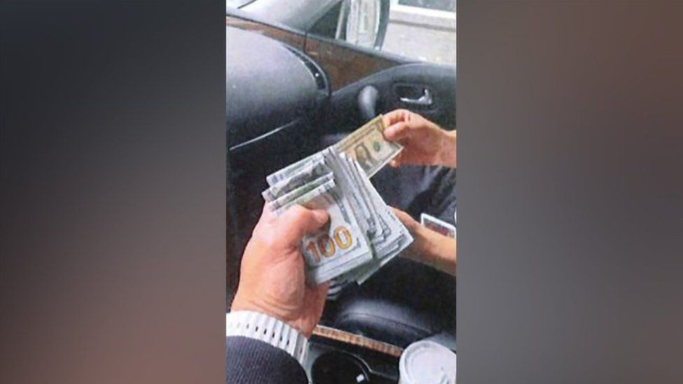 A wad of American cash held by a law enforcement official.
