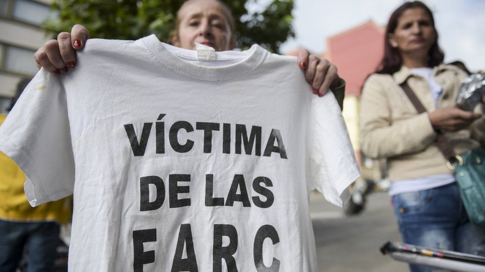 A woman holds a T-shirt reading "Victim of the FARC" during a protest in Bogota on 13 July 13 2018