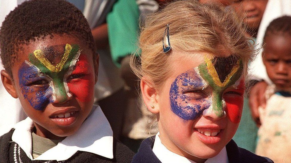 Two children have their faces painted in the colors of the national flag, 30 August 1996 in Warrenton, north of Capetown, where South-African president Nelson Mandela is going to inaugurate a school