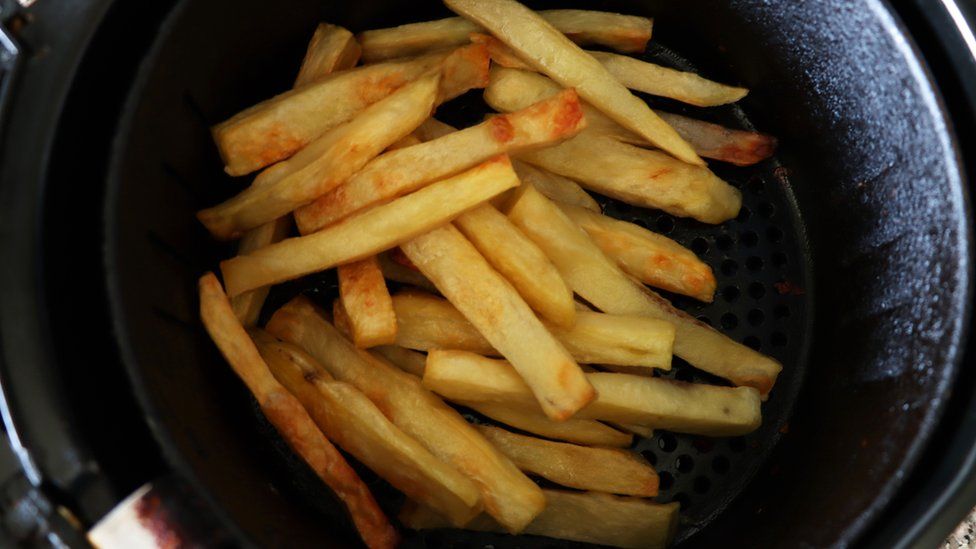 The inside of an air fryer with a pile of French fries