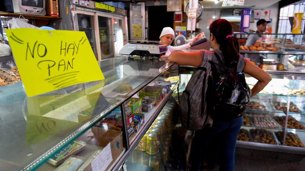 A woman waits at a bakery displaying a sign reading 'No Bread', in Caracas on February 25, 2016.