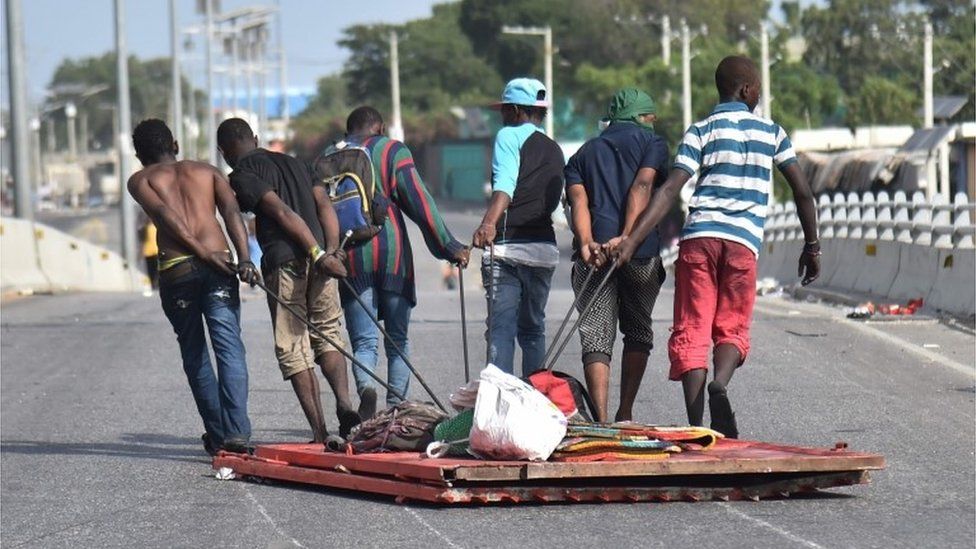 Looters carry away items in Delmas, a commune near Port-au-Prince, during protests against the rising price of fuel, on July 8, 2018.