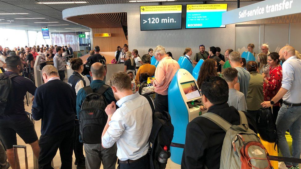 Passengers and staff wait for updates at Amsterdam's Schiphol airport on 24 July 2019