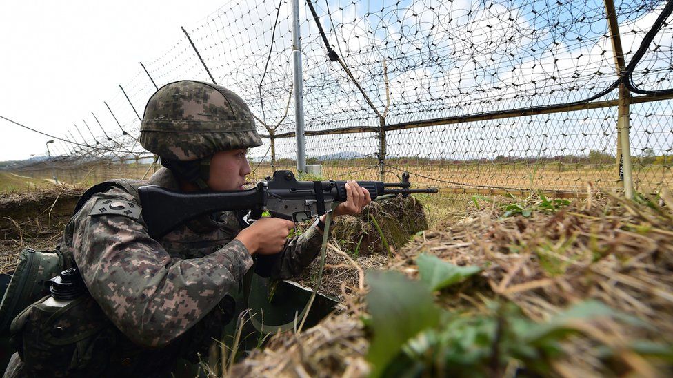 A South Korean soldier stands guard in front of a military fence at a General Outpost (GOP) of the Demilitarized Zone dividing the two Koreas in Cheorwon on October 13, 2015.