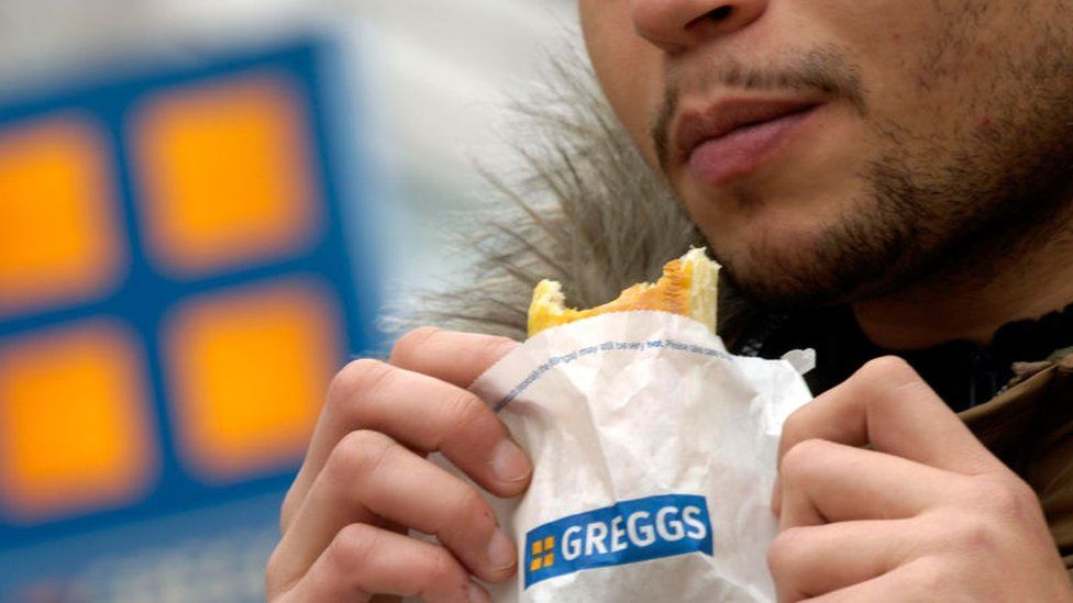 Man eating a Greggs sausage roll