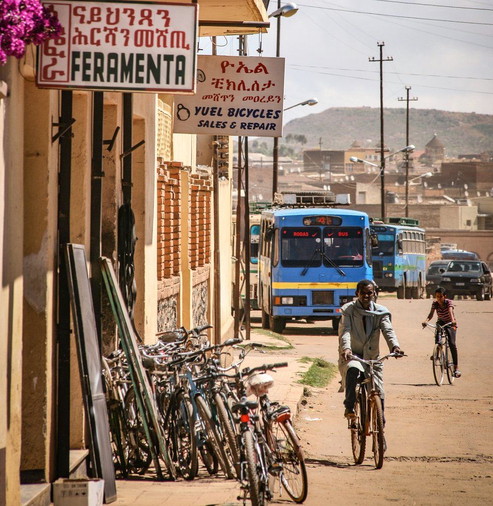 A man on a bicycle riding past a bike repair shop in Asmara, Eritrea