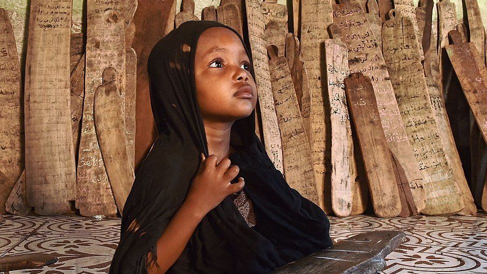 A girl in a madrassa holds a wooden board with verses of the koran written on it in Mogadishu, Somalia - 2015
