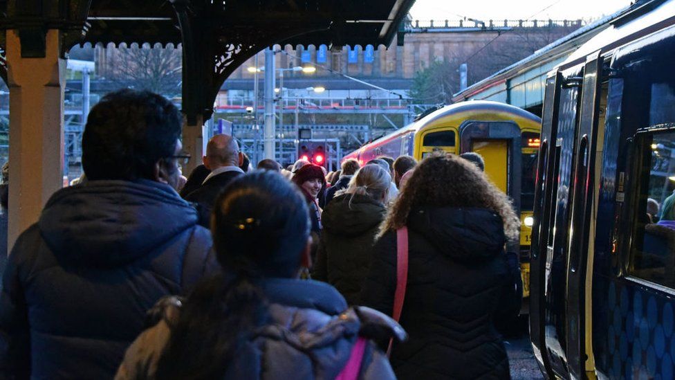 Passengers queue to board a train