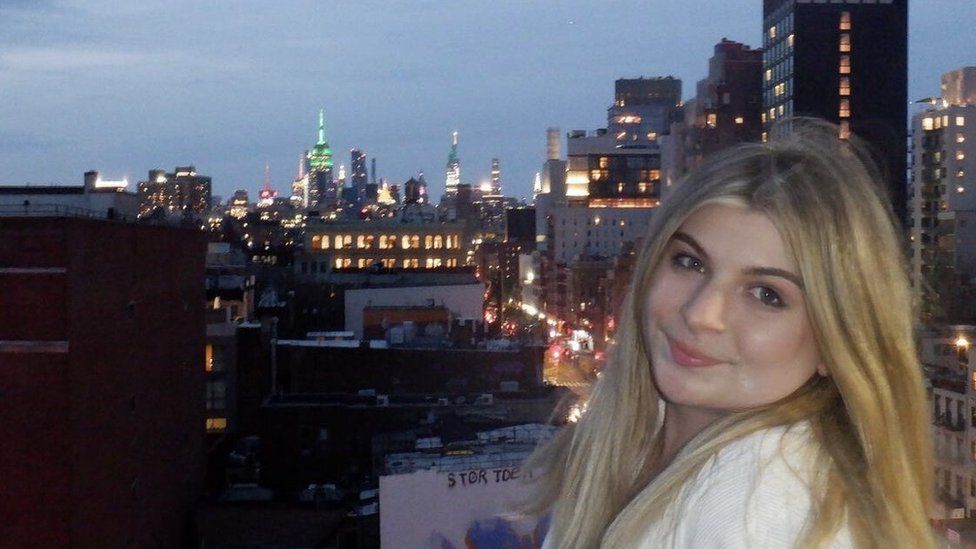 Sophie Singer smiling at the camera, in front of a city skyline
