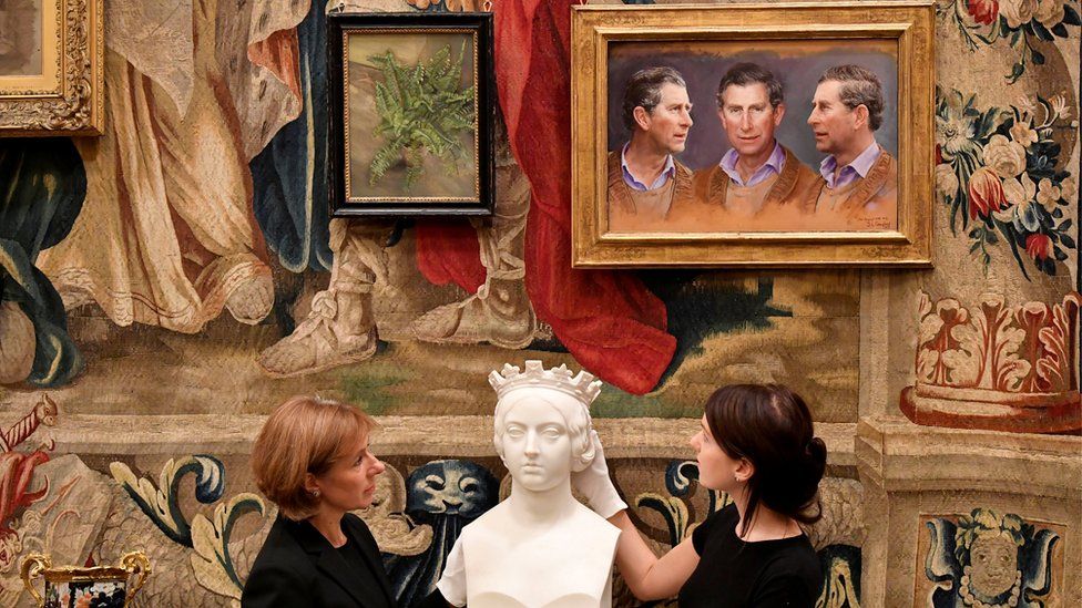 a bust before a wall of paintings