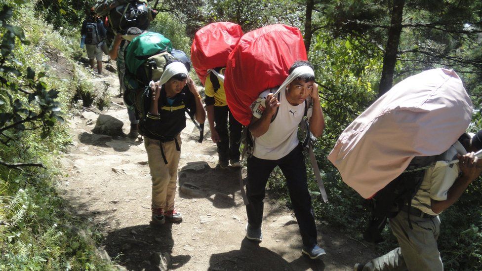 Teenagers working as porters carry heavy loads up to Everest Base Camp