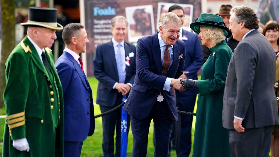 Queen Camilla greets sculptor Tristram Lewis during a ceremony to unveil a statue of jockey Frankie Dettori