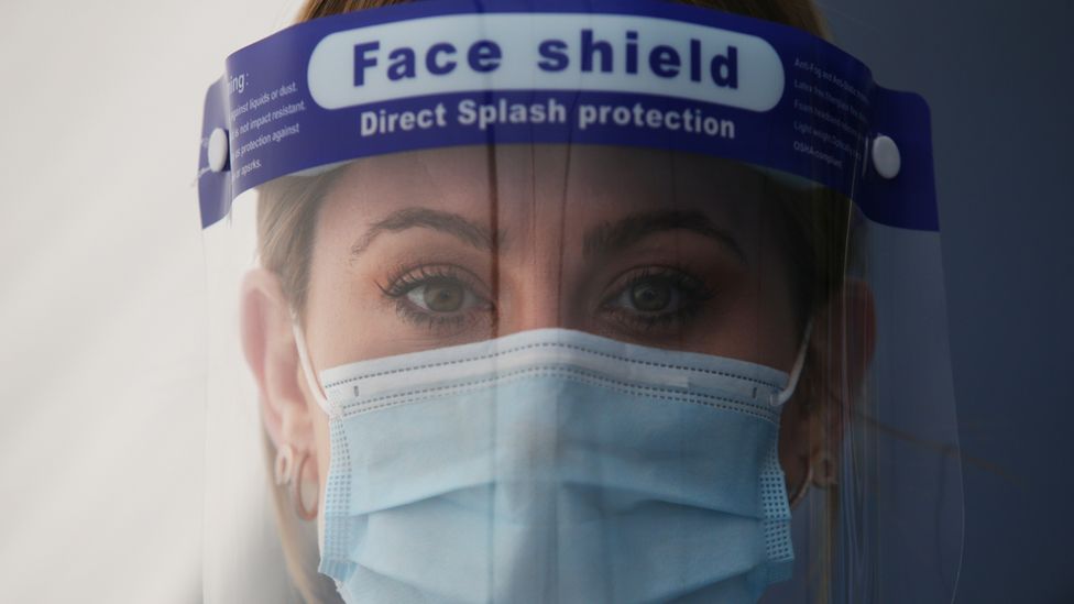 Female healthcare worker wearing full protective gear looks straight at the camera