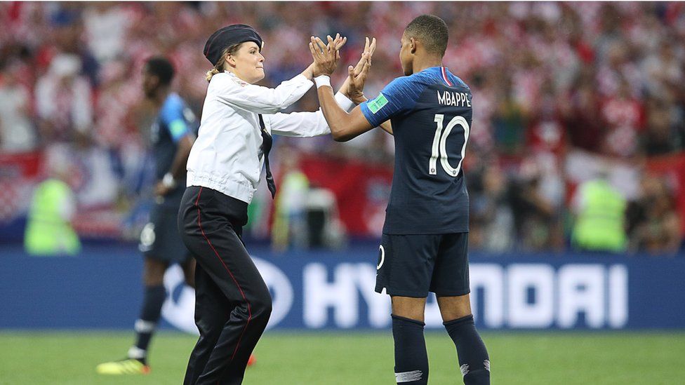A pitch invader high fives France's Kylian Mbappé during the 2018 FIFA World Cup final football match between France and Croatia, 15 July 2018