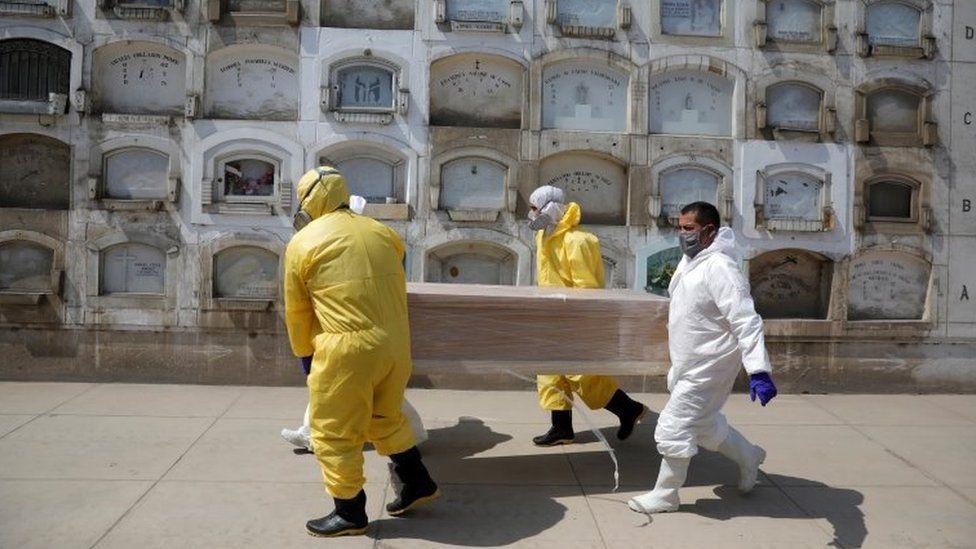 Funeral workers carry a coffin holding the body of a person who died of the coronavirus disease (COVID-19), at a cemetery in Lima, Peru, May 9, 2020.