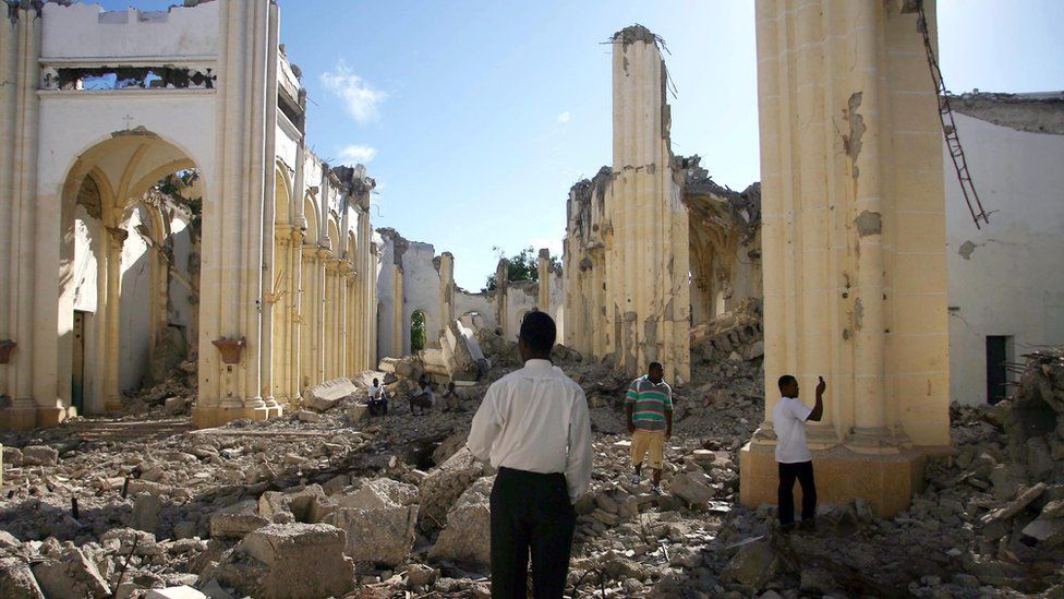 Haitians walk through the remains of the Notre Dame Cathedral in Port-au-Prince on the first anniversary of the 2010 quake