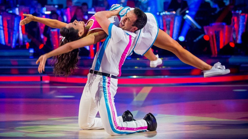 Will Bayley and Janette Manrara during a Strictly dance, with Will on his knees lifting Janette, who his horizontal across his shoulder