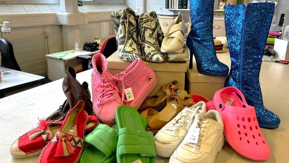 A number of different types of shoes, including blue high-heeled boots
