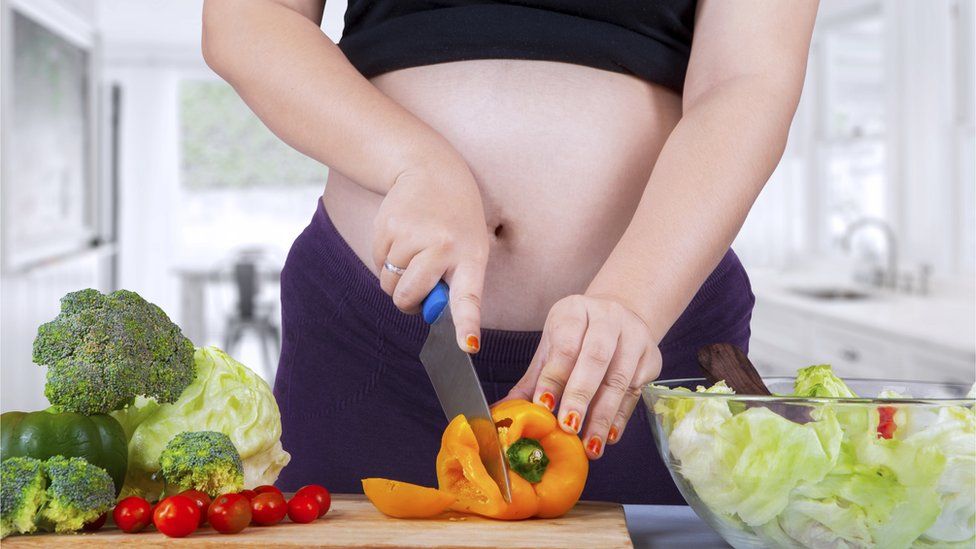 Pregnant woman prepares salad