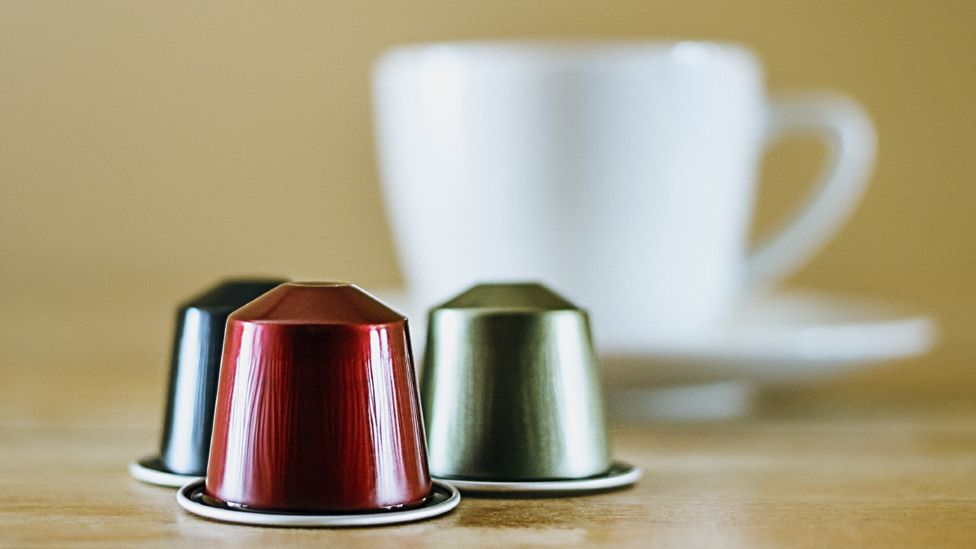 Coffee capsules in front of a coffee cup