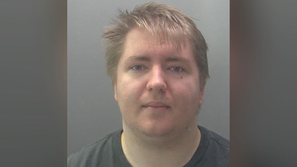 Lorcan Elliott's mugshot, he is wearing a grey T-shirt and staring straight at the camera. 