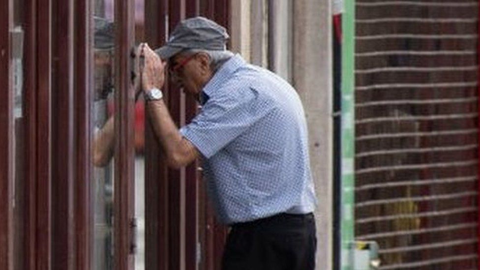 A man looks into the window of a closed coffee shop in Cardiff