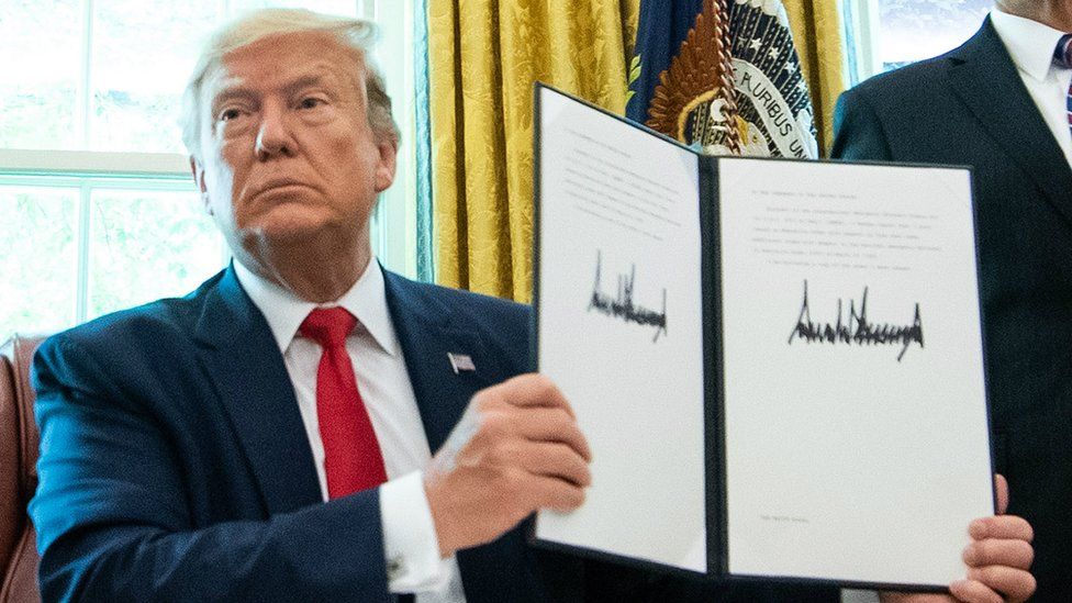 US President Donald Trump holds a copy of an executive order for additional sanctions against Iran at the White House on 24 June 2019