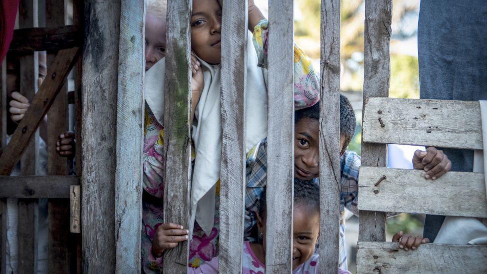 Curious children watch through a wooden fence in Fort Dauphin, Madagascar