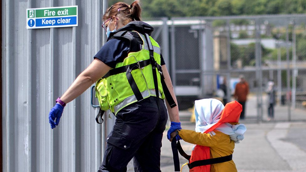 A young child is led to an intake facility after arriving in Kent