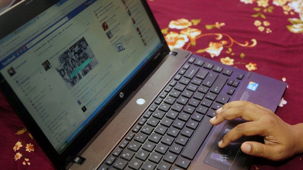 A Bangladeshi woman logging onto Facebook on a laptop