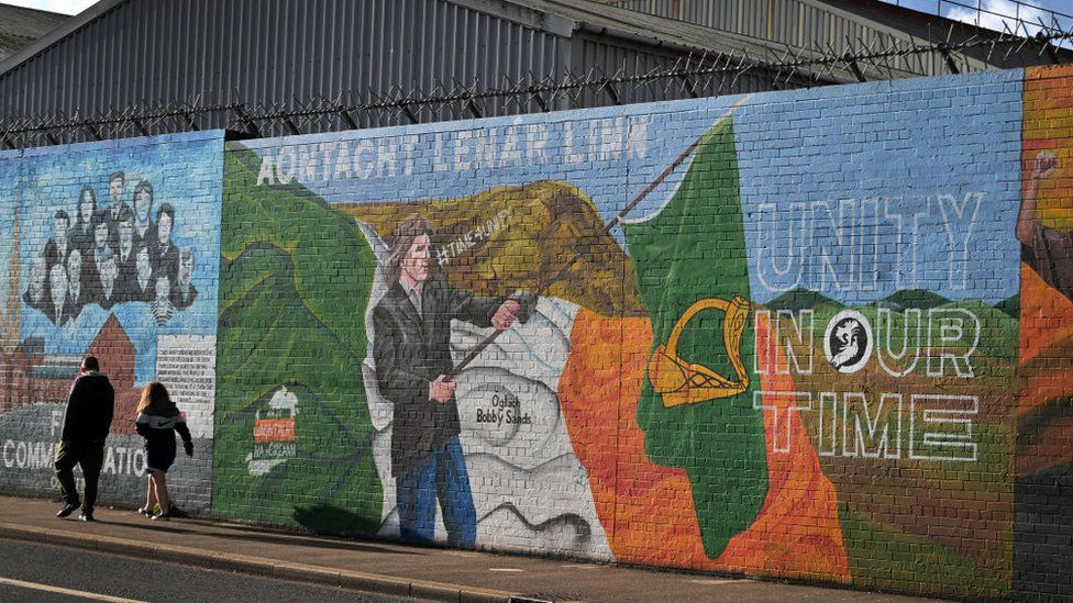 People walk past a mural calling for Irish unity