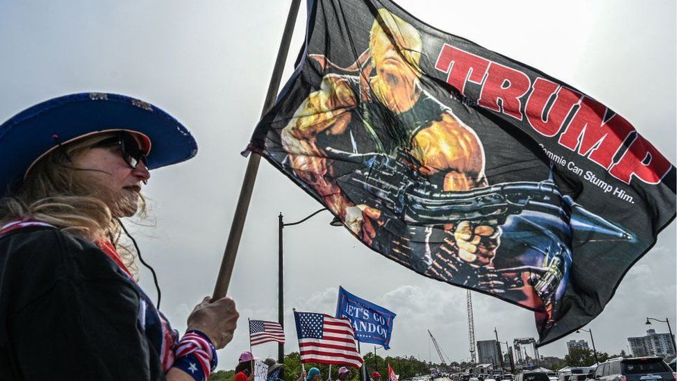 Поклонник Трампа из Флориды держит флаг, на котором он изображен в образе Рэмбо, звезды боевиков