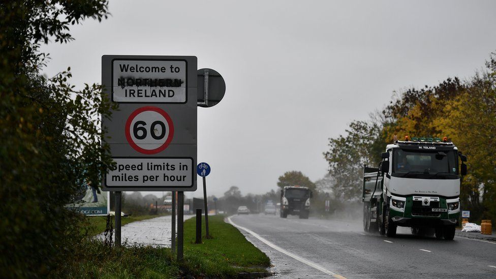 Traffic moves by a defaced "Welcome to Northern Ireland" sign on the Irish border on October 9, 2018