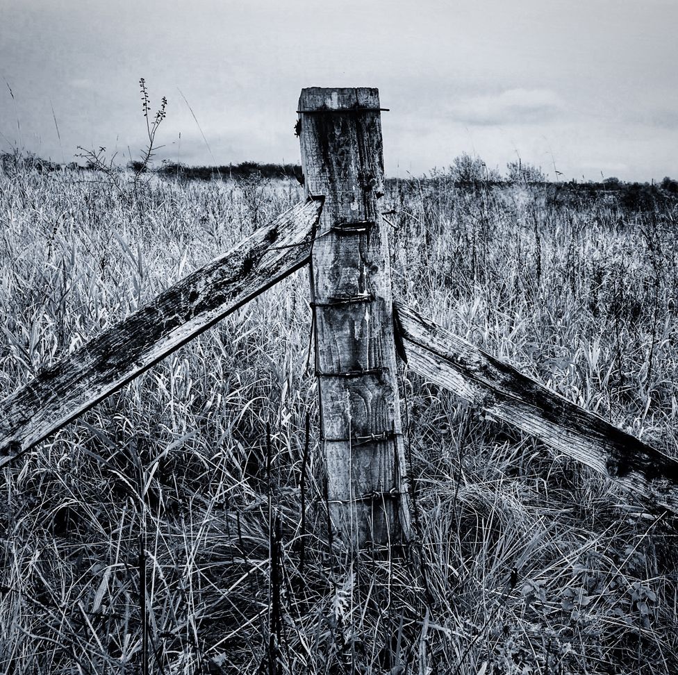 A black and white photo fo an old fence