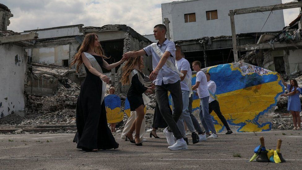 School graduates dance in front of destroyed building in the Kharkiv region, Ukraine. Photo: June 2023