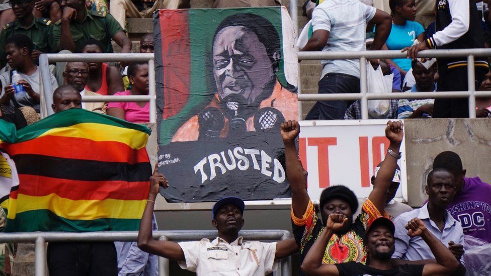 Supporters hold a portrait of Zimbabwe's new President Emmerson Mnangagwa during his inauguration on 24 November 2017 in Harare