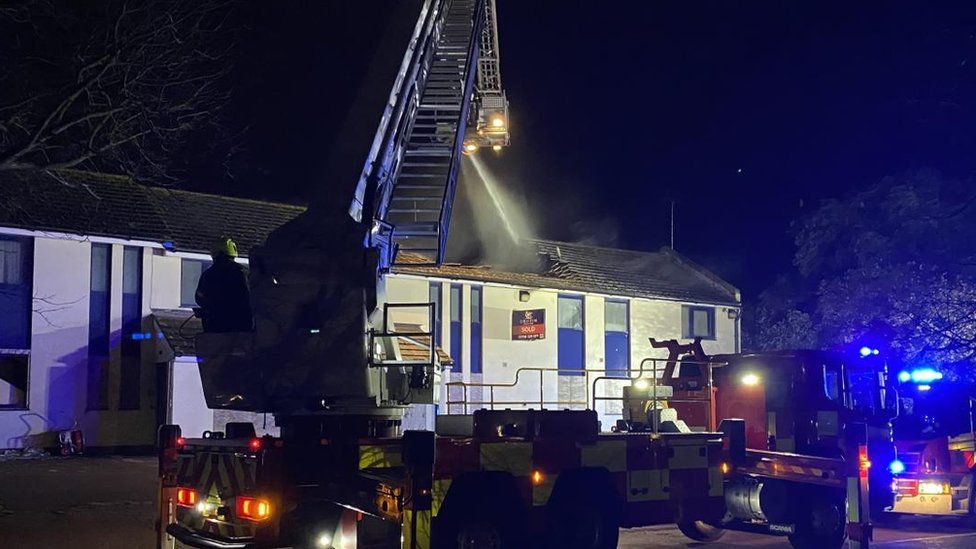 Firefighters and engines parked outside a white building after receiving reports of a fire