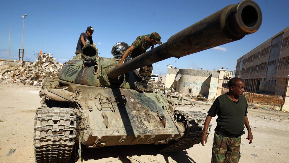 A picture taken on 9 November 2017 shows members of the self-styled Libyan National Army, loyal to the country's east strongman Khalifa Haftar, riding on a tank as it drives down a street in Benghazi