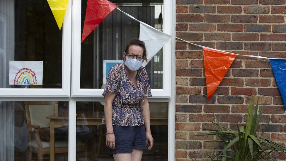 A woman wearing a face mask outside a house in Bedford