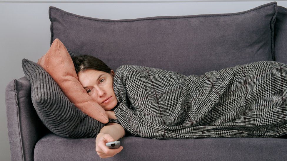 Woman lying on sofa feeling very tired