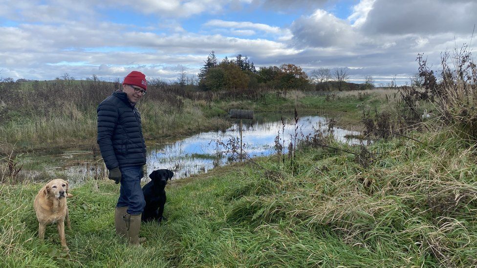 Charlie Bennett and two dogs in front of one of 14 ponds he's created