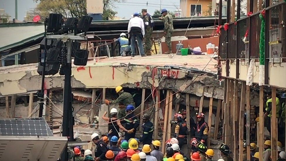 Rescuers ask a teacher (centre, with white helmet) to help communicate with a young girl they believed was trapped alive inside, Mexico City, 20 September 2017