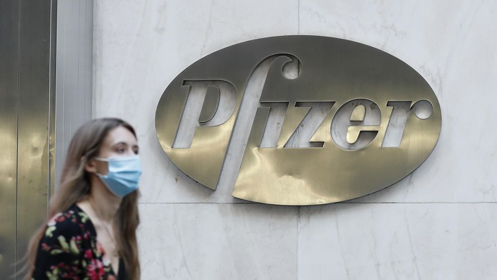 Woman walks past Pfizer sign