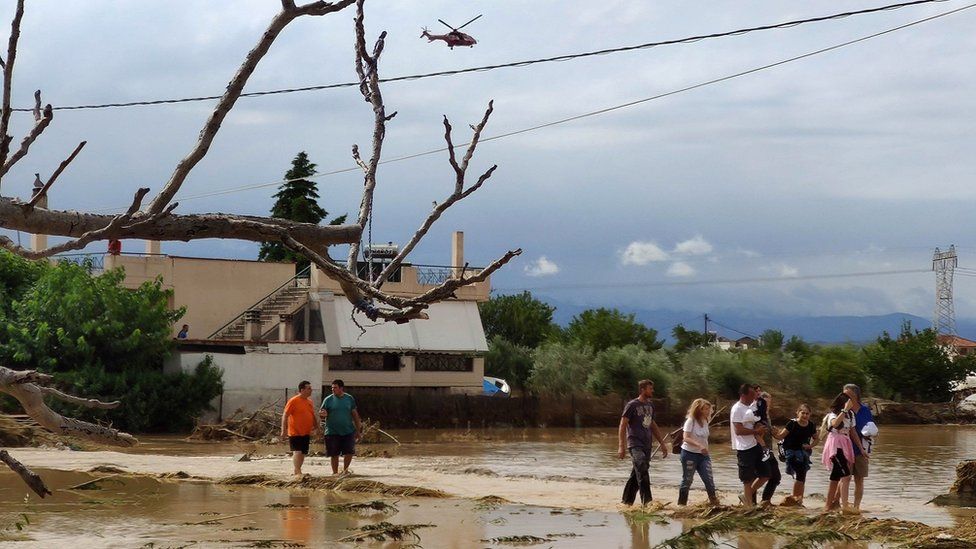 Residents leave their flooded houses after a rainstorm hit the area of Mourtzi, in Evia Island, Greece, 09 August 2020.