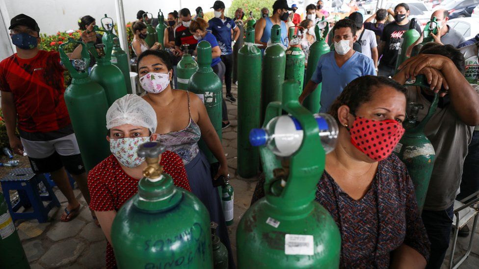 Родственники госпитализированных или получающих медицинскую помощь пациентов на дому собираются, чтобы купить кислород и заправить баллоны в частной компании в Манаусе