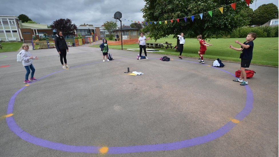 Children dance on a measured and painted socially distanced circle in the playground as they wait to be picked up by their parents at Llanishen Fach Primary School in Cardiff