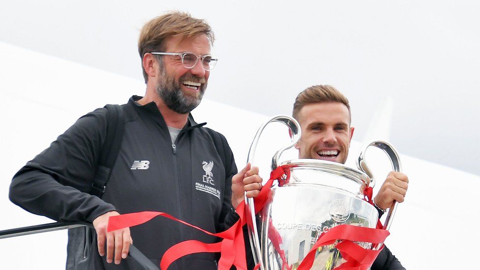 Jurgen Klopp and Jordan Henderson hold aloft the cup as they come out of the plane at Liverpool Airport