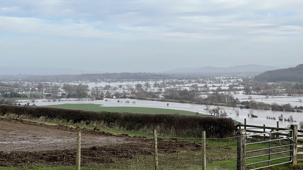Floods across fields and farms with hills in the distance