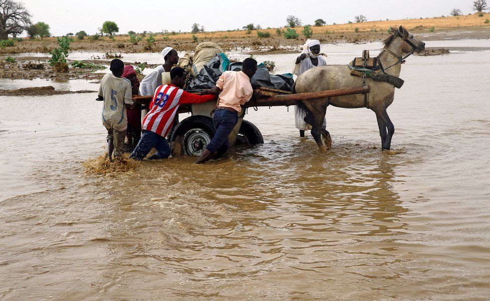 Displaced people carry their belongings to get away from flood during heavy rain at Nyala locality in South Darfur, Sudan 3 June 2017.