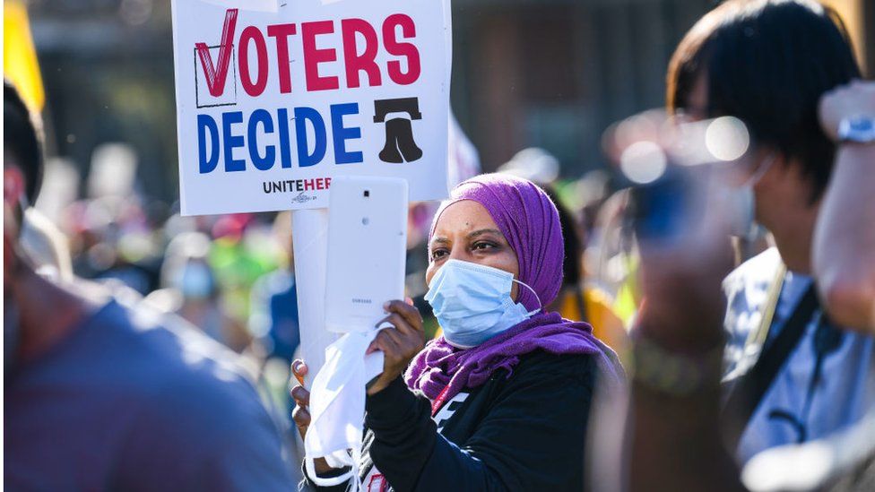 A protester holds a sign reading "voters decide" during an eleciton rally in Philadelphia